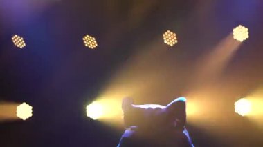 Genç adam kulüpte tek başına dans ediyor, neon ışıklı, dumanlı. Breakdance yakın çekim. Siluet.