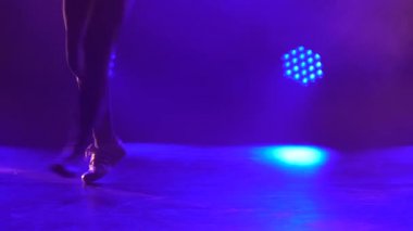 Genç break dans dansçısı karanlık bir stüdyoda yerde dans eder. Sahne ışıkları altında dinamik olarak dans eden bir adamın silueti. Kapat..