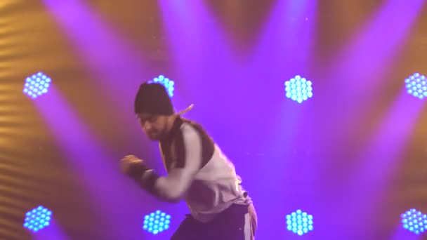 Man danseres breakdance, hiphop, straatdansen in de studio, geïsoleerd. Een jongeman voert breakdance elementen uit in een donkere studio met paarse achtergrondverlichting. Sluiten.. — Stockvideo