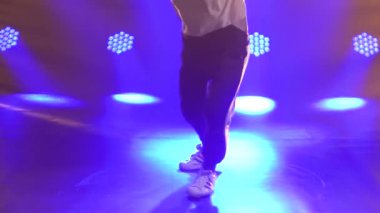 Erkek dansçı break dans, hip hop, stüdyoda sokak dansı, izole. Genç bir adam mor ışıklandırmalı karanlık bir stüdyoda break dans yapıyor. Kapatın. Yavaş çekim.