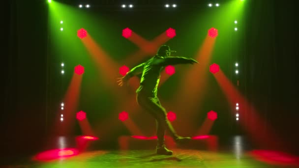 Die junge Streetdance-Tänzerin tanzt gerne in einem dunklen Studio. Silhouette in den Strahlen farbiger Neonlichter. Zeitlupe. — Stockvideo