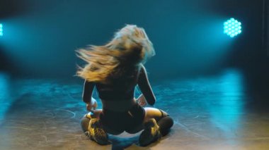 Stüdyoda dans eden bir kadının arka plan görüntüsü. Mavi ışıklarla kaplı dumanlı arka planda ince bir vücudun silueti. Kapatın. Yavaş çekim.