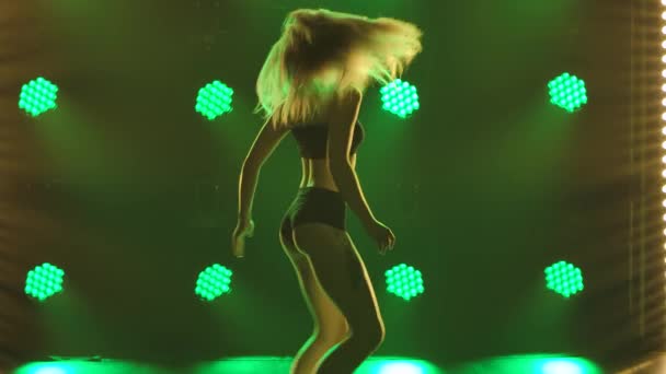 Mujer bailarina sacude un botín bailando twerk. Hermosas mujeres bailando booty dance. Silueta de un delgado cuerpo semidesnudo en los rayos verdes de focos. De cerca. Movimiento lento. — Vídeos de Stock