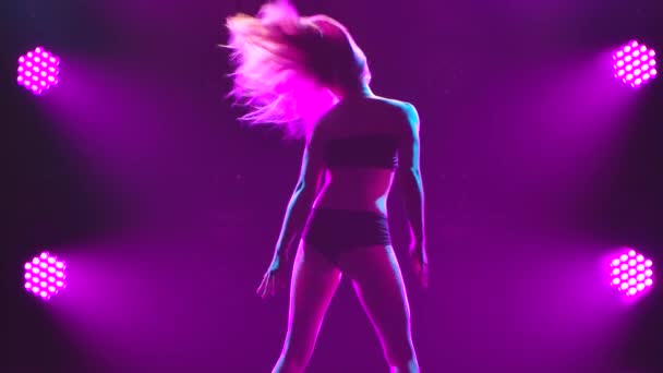Hermosa mujer bailando y twerking mientras usa top negro y bragas. Silueta sobre el fondo de luces púrpuras. De cerca. Movimiento lento. — Vídeos de Stock