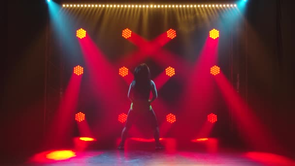 Sylwetka brunetka energicznie tańczy i twerkuje na tle czerwonych neonów. Zwolniony ruch. — Wideo stockowe