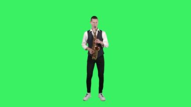 Portre stili genç adam stüdyodaki yeşil ekranda saksafonda hızlı melodi çalıyor. Saxophonist solo performans sergiliyor.