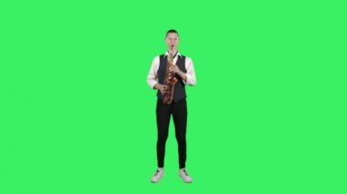 Portre stili genç adam stüdyodaki yeşil ekranda saksafonda yavaş melodi çalıyor. Saxophonist solo performans sergiliyor.