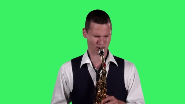 Portrait stylish young guy plays fast melody at saxophone on a green screen in the studio. Saxophonist performing a solo. Close up. — Stock Video