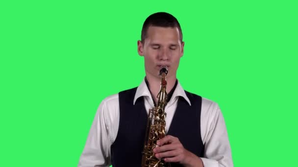 Portrait stylischer junger Kerl spielt langsame Melodie am Saxofon auf einer grünen Leinwand im Studio. Saxofonist mit einem Solo. Nahaufnahme. — Stockvideo