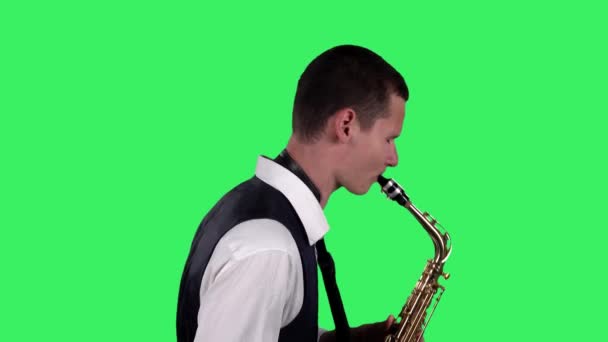 Portrait stylish young guy plays at saxophone on a green screen in the studio. Saxophonist performing a solo. Side view. Close up. — Stock Video