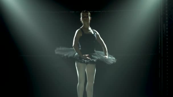 Silhuett en ung ballerina i svart tutu och pointe balett skor. Graciös dans av element klassisk balett. Skjuten i ett mörker under en teater spotlights på svart bakgrund av studio. — Stockvideo