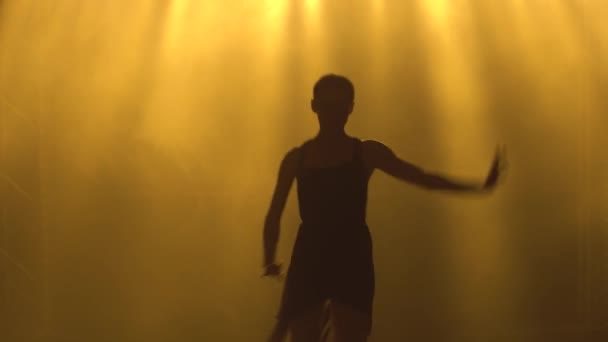 Professionelle Ballerina tanzt Ballett im Scheinwerferlicht und raucht auf der Bühne. Silhouette einer schönen schlanken Figur. — Stockvideo