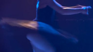 Siluet siyah etekli ve sivri uçlu balerin ayakkabılı genç bir balerin. Klasik bale elementlerinin zarif dansı. Stüdyonun sahne ışıkları altında karanlıkta çekilmiş. Kapat..