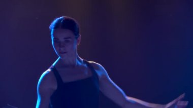 Siluet siyah etekli ve sivri uçlu balerin ayakkabılı genç bir balerin. Klasik bale elementlerinin zarif dansı. Stüdyonun sahne ışıkları altında karanlıkta çekilmiş. Kapat..