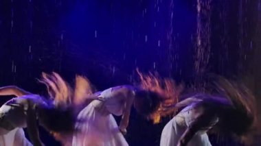 Uzun beyaz elbiseli üç kadın dumanlı arka planda yağmurda güllerle dans ediyorlar. Ağır çekim. Kapat..
