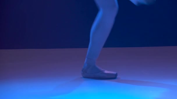 Egy pointe cipős balerina kecses lábai. Sötétben lőtték le a stúdió reflektorfényeiben. A balerina klasszikus balett pas-t mutat. Közelről.. — Stock videók