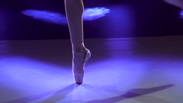 Блискучі ноги балерини в точкових туфлях. Розстріляний у темряві на задньому плані студії. Балерина демонструє класичний балет пас. Зачиніть.. — стокове відео