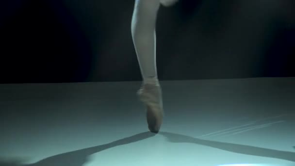 Χαριτωμένα πόδια μπαλαρίνας σε pointe παπούτσια. Πυροβολήθηκε σε ένα σκοτάδι σε προβολείς φόντο στούντιο. Μπαλαρίνα δείχνει κλασικό pas μπαλέτου. Κλείσε.. — Αρχείο Βίντεο