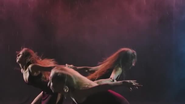 Μια ομάδα γυναικών με μακριά φορέματα χορεύουν μοντέρνα χορογραφία σε ένα καπνιστό backlit studio. Αργή κίνηση. Κλείσε.. — Αρχείο Βίντεο