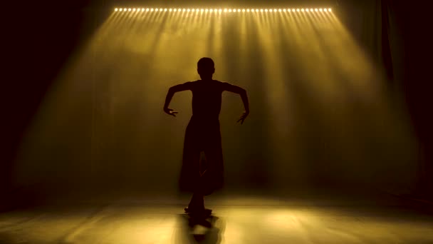 Profesyonel balerin sahne ışıkları altında bale yapıyor ve sahnede sigara içiyor. Güzel, ince bir siluetin silueti. Yavaş çekim. — Stok video