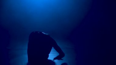 Çalışkan, genç, zarif balerin klasik balerin unsurları. Arka planda ışık ve dumanla karanlıkta çekilmiş. İnce, genç bir kız siluetlendi. Yavaş çekim.