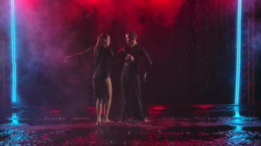 Yağmurda tutkulu bir çift tarafından yapılan caz müzikleri. Karanlık bir stüdyoda, renkli ışıklandırmalı dumanlı bir arka planda çekilmiş. Yavaş çekim.