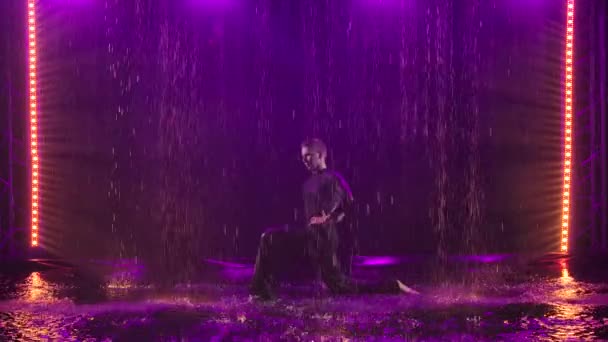 Jive στοιχεία εκτελούνται από ένα παθιασμένο ζευγάρι στη βροχή. Φωτογραφήθηκε σε σκοτεινό στούντιο πάνω σε καπνιστό φόντο με μωβ φωτισμό. Αργή κίνηση. — Αρχείο Βίντεο