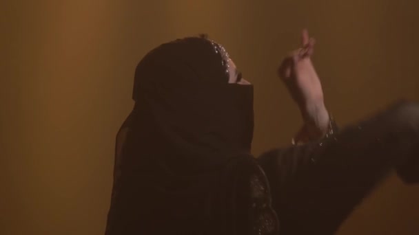 Silhouette pancia esotica ballerina donna che danza in un abito orientale nero e hijab. Girato in uno studio buio con fumo e luci al neon. Da vicino.. — Video Stock