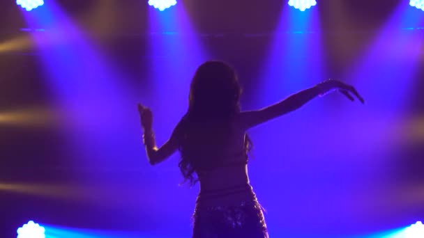 Baştan çıkarıcı, geleneksel oryantal dansçı kız mavi neon duman arka planında dans ediyor. İnce, esnek bir vücudun siluetleri. Kapat.. — Stok video