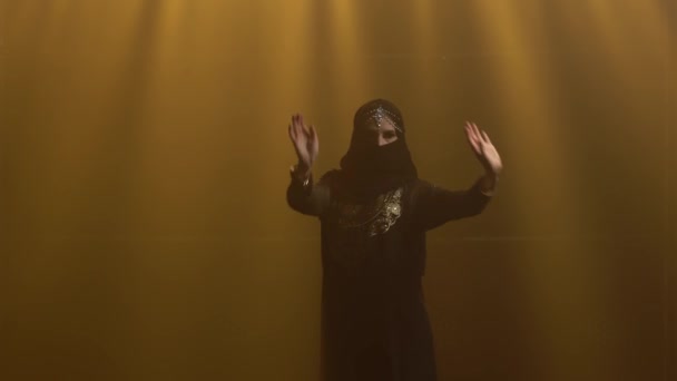 Siluet dansçı kadın siyah oryantal elbise ve tesettür içinde dans ediyor. Duman ve neon ışıkla karanlık bir stüdyoda çekildi. Kapat.. — Stok video