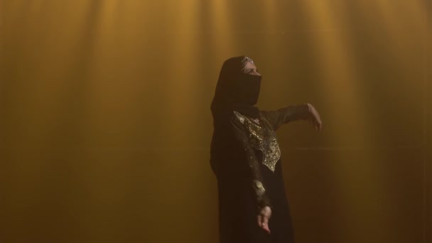 Bailarina de vientre Silhouette bailando con un vestido oriental negro y hijab. Grabado en un estudio oscuro con humo e iluminación de neón. De cerca.. — Vídeos de Stock