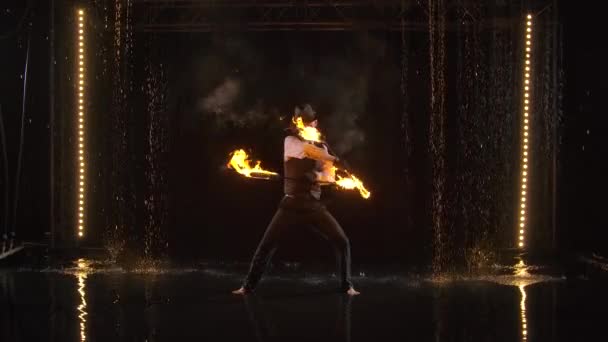 Vzrušující noční požární show provedená stylovým mužem vystupujícím v dešti. Silueta fakíra na černém pozadí s inscenovaným světlem studia. Zpomalený pohyb. — Stock video