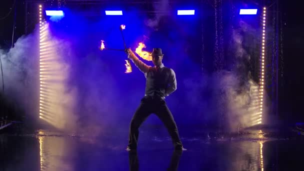 Fireshow performance met brandende fakkel uitgevoerd door een man in een pak en hoed. Vuurshow in de regen in de studio. Langzame beweging. — Stockvideo