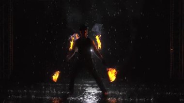 Yağmurda karanlık bir stüdyoda profesyonel bir yangın gösterisi yapan bir adamın silüeti. Yavaş çekim.