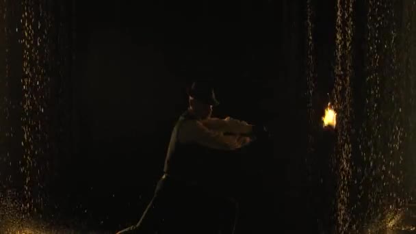 Male fire tamer in a thrilling close-up fire show in a dark studio in the rain. A silhouette of a man swinging fiery balls on chains in slow motion. — Stock Video