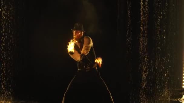 Mannelijke vuurmaker in een spannende close-up vuurshow in een donkere studio in de regen. Een silhouet van een man swingende vurige ballen op kettingen in slow motion. — Stockvideo