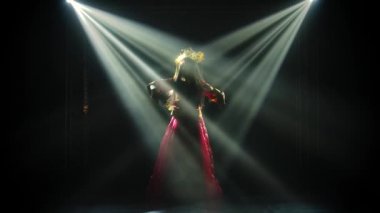 Kırmızı ipek kostüm içinde güzel bir kadın ve Çinli bir prensesin başlığı sahnede zarif bir şekilde dans ediyor. Neon ışıkları altında siluetler beliriyor. Yavaş çekim.