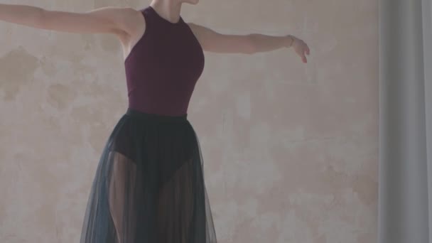Bella giovane ballerina in abito da palcoscenico nero prova mosse di danza. Lezione di danza in studio con pavimenti in parquet bianco. Chiudete. Rallentatore. — Video Stock