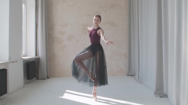 Rendimiento profesional de una bailarina frágil sobre el fondo de grandes ventanas y cortinas panorámicas. Filmado en un estudio tipo loft bañado por la luz del día. Movimiento lento. — Vídeos de Stock