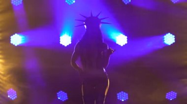 Gece kulübü kıyafetiyle dans eden seksi esmer Amerikan Özgürlük Heykeli. Koyu arkaplan ve dinamik mavi ışıklar. Siluet. Git dansçı gösterisi yap. Kapat..