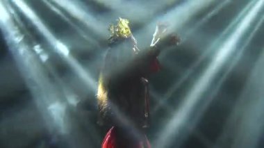 Çekici aktris el hareketlerini ve danslarını sergiliyor. Kırmızı ipek takım elbiseli parlak bir esmer ve Çinli bir prensesin başlığı. Kapat..