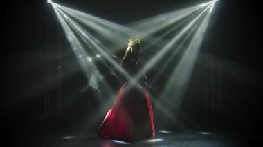 Çekici aktris el hareketlerini ve danslarını sergiliyor. Kırmızı ipek takım elbiseli parlak bir esmer ve Çinli bir prensesin başlığı. Yavaş çekim.