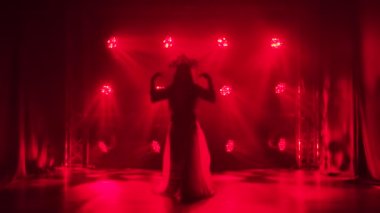 Bir kadın dansçı kırmızı ışıklarda ve dumanda dans ederken siluete bürünür. Kırmızı ipek takım elbiseli parlak bir esmer ve Çinli bir prensesin başlığı. Yavaş çekim.