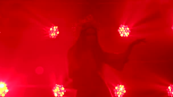 Uma dançarina é silhueta em luzes vermelhas e fuma fazendo uma dança folclórica. Uma morena brilhante em um terno de seda vermelho e uma cobertura para a cabeça de uma princesa chinesa. Fechar. — Vídeo de Stock