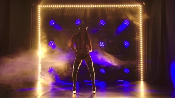 Kobieta tańcząca w ciemnym studio z dymem i niebieskimi neonami. Atrakcyjna brunetka w seksownym garniturze Amerykańska Statua Wolności. Zwolniony ruch. — Wideo stockowe