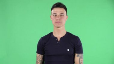 Yakışıklı bir gencin portresi kameraya bakar ve bir şeyi işaret eder. Yeşil Ekran.