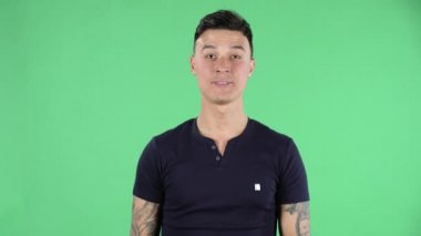 Yakışıklı bir gencin portresi kameraya bakıyor ve iki parmağıyla zafer işareti yapıyor. Yeşil Ekran.