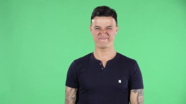 Yakışıklı bir gencin portresi kameraya bakıyor ve kötü kokudan ve zevkten tiksindiğini gösteriyor. Yeşil Ekran.