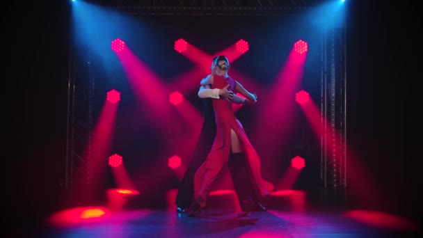 Junges Paar tanzt leidenschaftlich Tango in einem dunklen Raum mit Rauch und roten Scheinwerfern in Zeitlupe. — Stockvideo