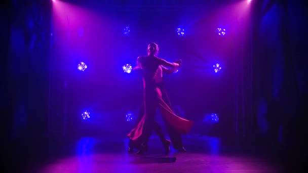 Knappe man en vrouw dansen latijns tango dansen tussen het prachtige licht. Silhouetten van dansers op een rokerige studio achtergrond in slow motion. — Stockvideo